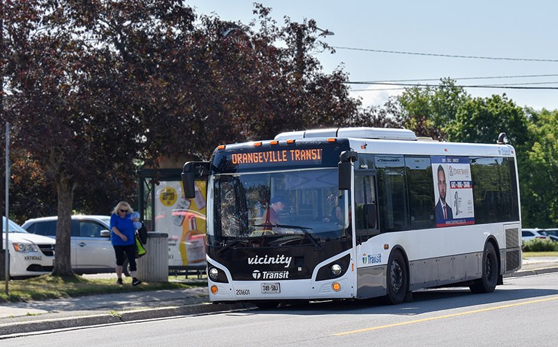 An Orangeville Transit bus picking up passengers from a bus shelter
